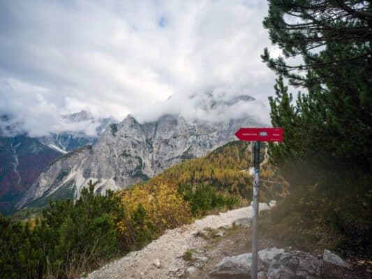 Mountain hut trail sign with scenic mountain landscape in the background.